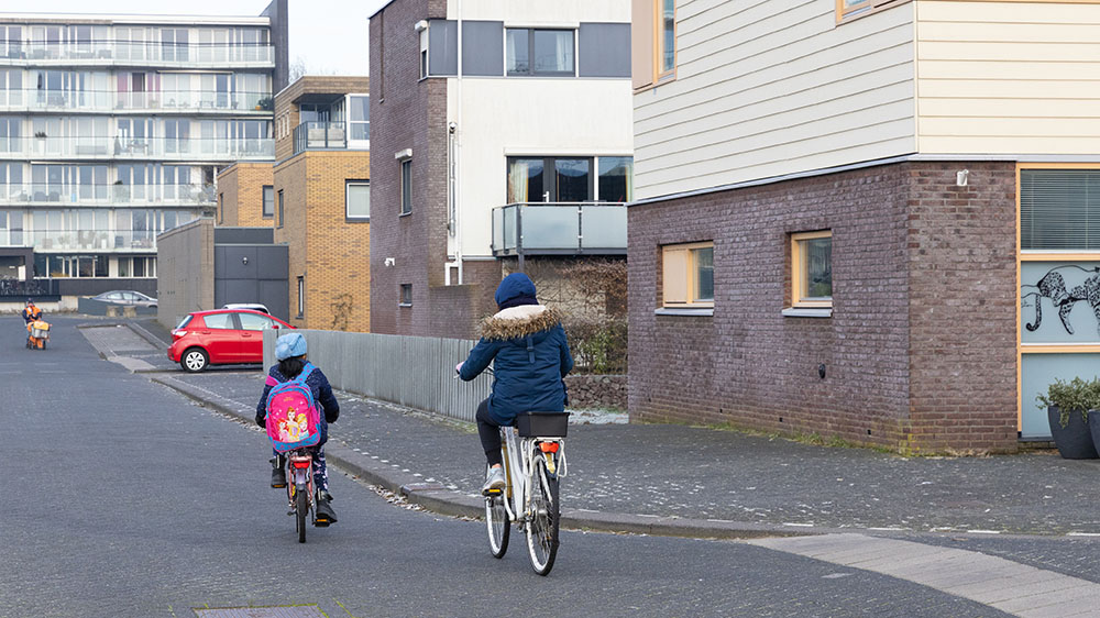 Twee mensen fietsen door een wijk